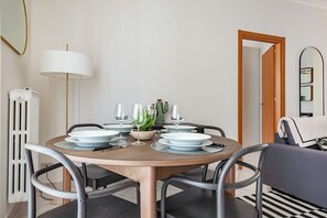 Un'area pranzo con un tavolo rotondo apparecchiato per quattro persone, circondato da sedie.