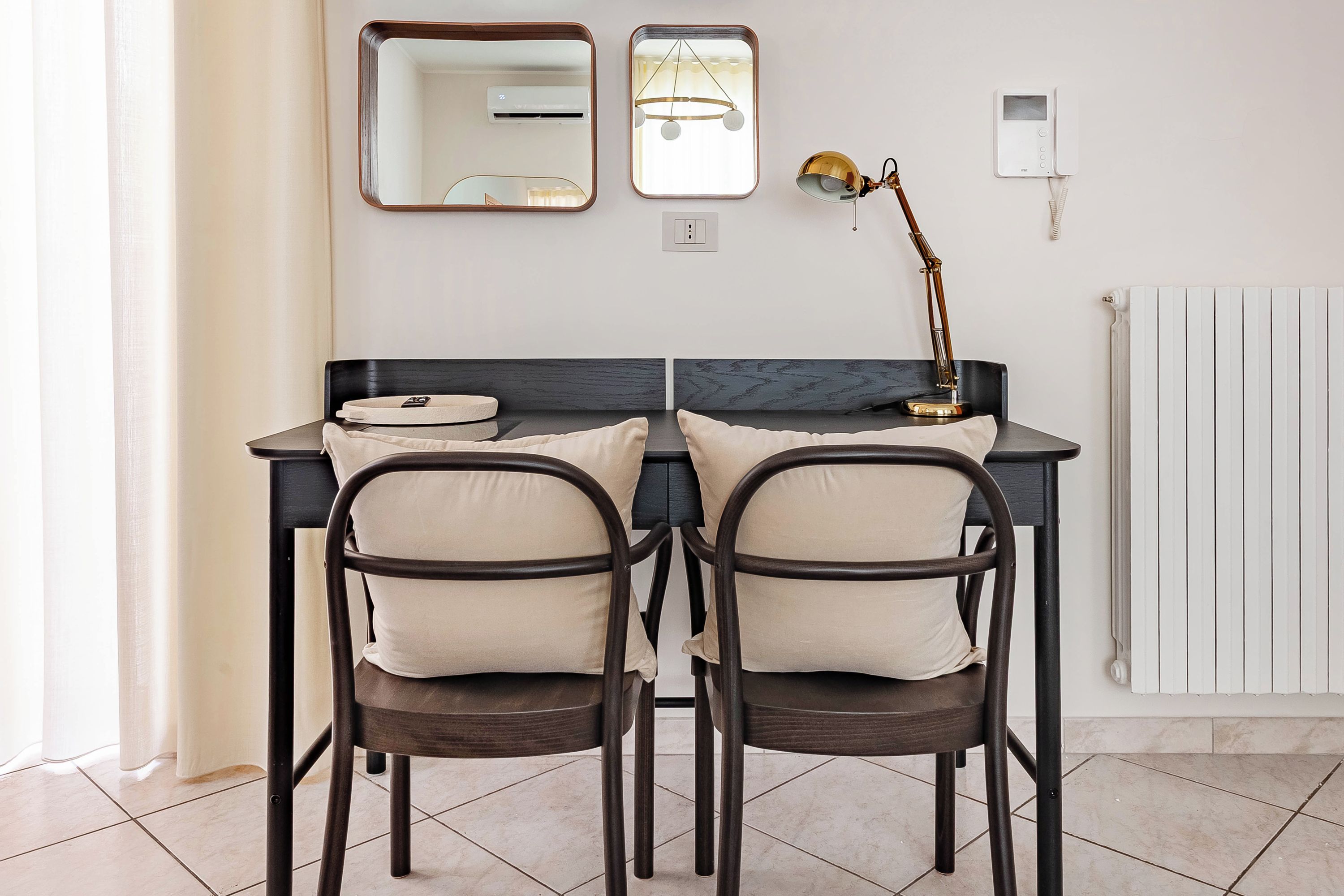 Una habitación moderna con escritorio, dos sillas, lámpara y radiador.