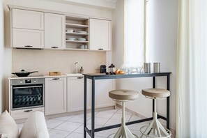Una cucina moderna con mobili bianchi, forno integrato e un'area pranzo con sgabelli.