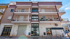A multi-story residential building with balconies, a garage, and a storefront. - Welcome Suite (Conversano)