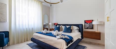 Un dormitorio moderno con una cama grande, una mesita de noche, una lámpara de noche, una silla y un candelabro.