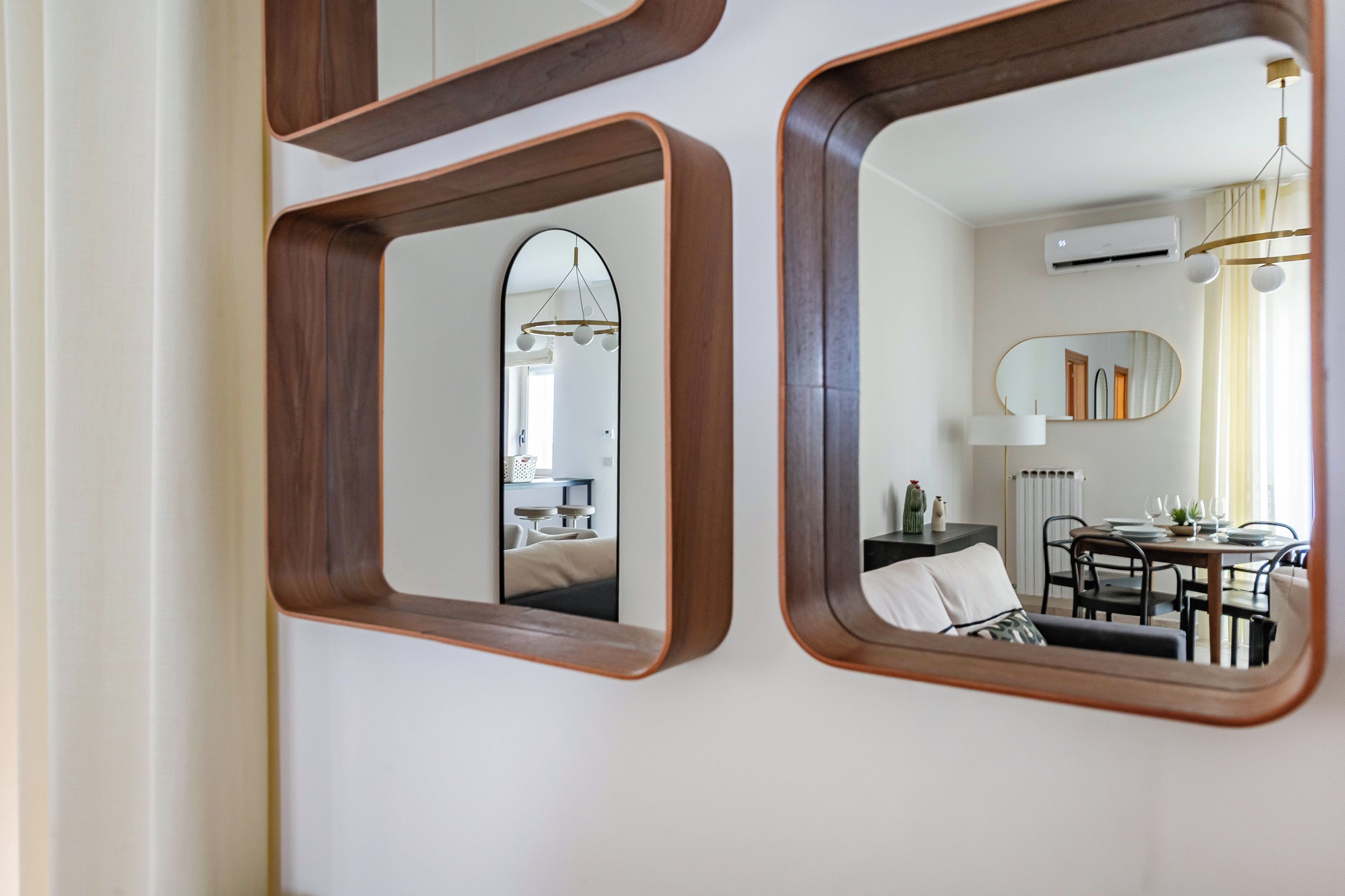 A wall with three mirrors of different shapes and sizes.