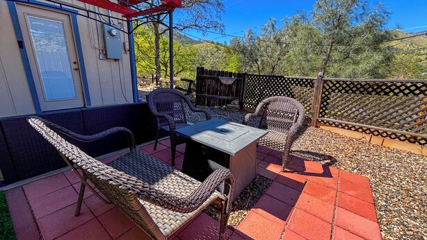 Une terrasse extérieure avec des meubles en osier, une table et une pergola rouge.