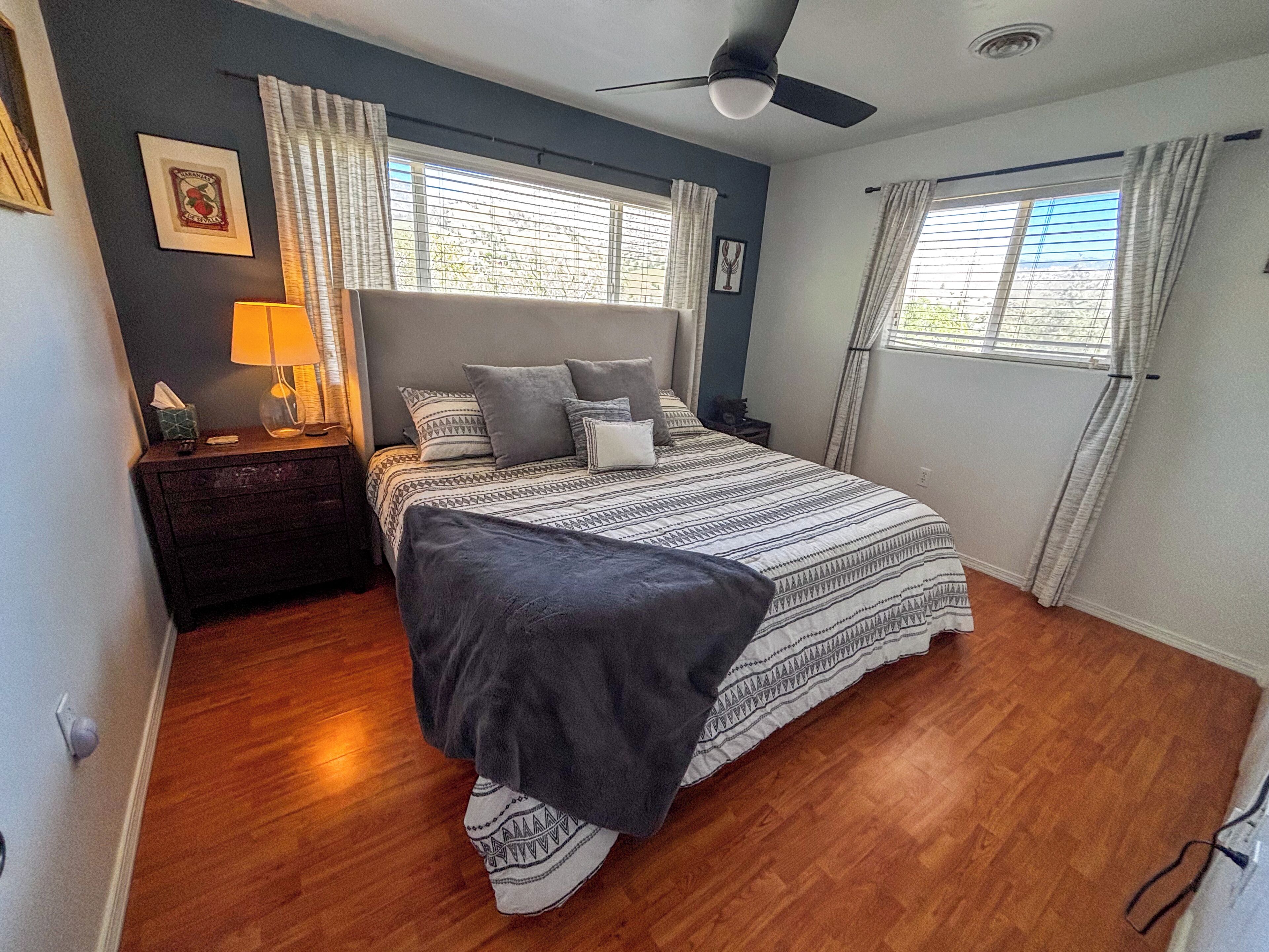 A bedroom with a bed, a nightstand, a lamp, and a ceiling fan.