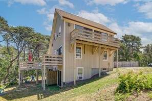 A two-story house with a balcony, a covered patio, and a fenced yard. - Sea Breeze, Sunset Views! Family Escape Near Ocean (Wellfleet)