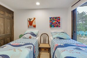 Ein Zimmer mit zwei Betten, jeweils mit einer blau-weißen Bettdecke, einer Holztür und zwei an der Wand hängenden Bildern.