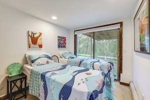Une chambre à coucher avec un lit recouvert d’une couvre-lit à motifs bleus et blancs, une pancarte d’accueil verte et une fenêtre donnant sur des arbres.