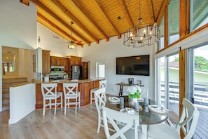 A spacious kitchen with wooden cabinets, a central island, and a dining area with white chairs. - Island Oasis w/ Hot Tub, Walk to Shops and Dining (Marco Island)
