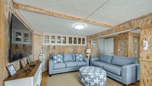 Een woonkamer met een modulaire bank, een voetenbankje en ingebouwde planken met decoratieve objecten.