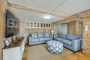 Ein Wohnzimmer mit Ecksofa, Hocker und einer Einbauwand mit Dekorationselementen.