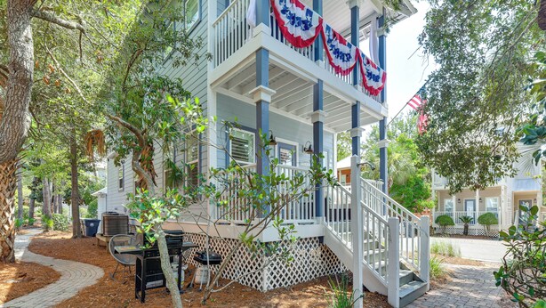 A two-story house with a balcony, surrounded by trees and a garden. - Walkable 30A Beach House: 2 Community Pools, Bikes (Santa Rosa Beach)