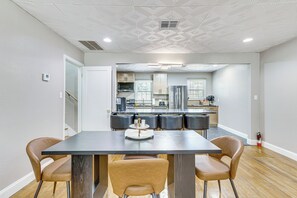 A modern kitchen with a central island, stainless steel appliances, and a dining area with a dark table and leather chairs.