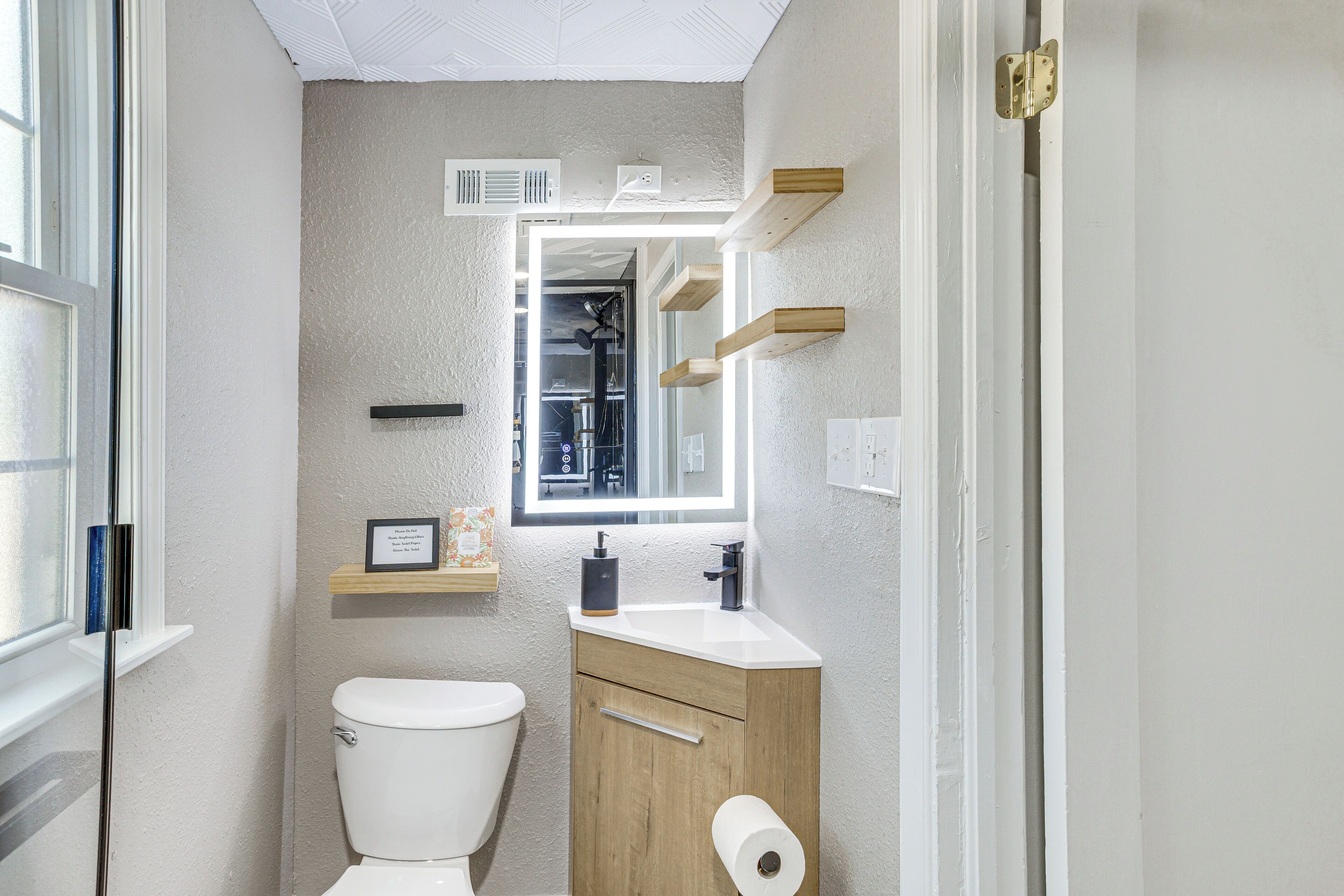 A compact bathroom with a toilet, sink, and mirror.