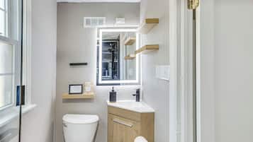 A compact bathroom with a toilet, sink, and mirror.