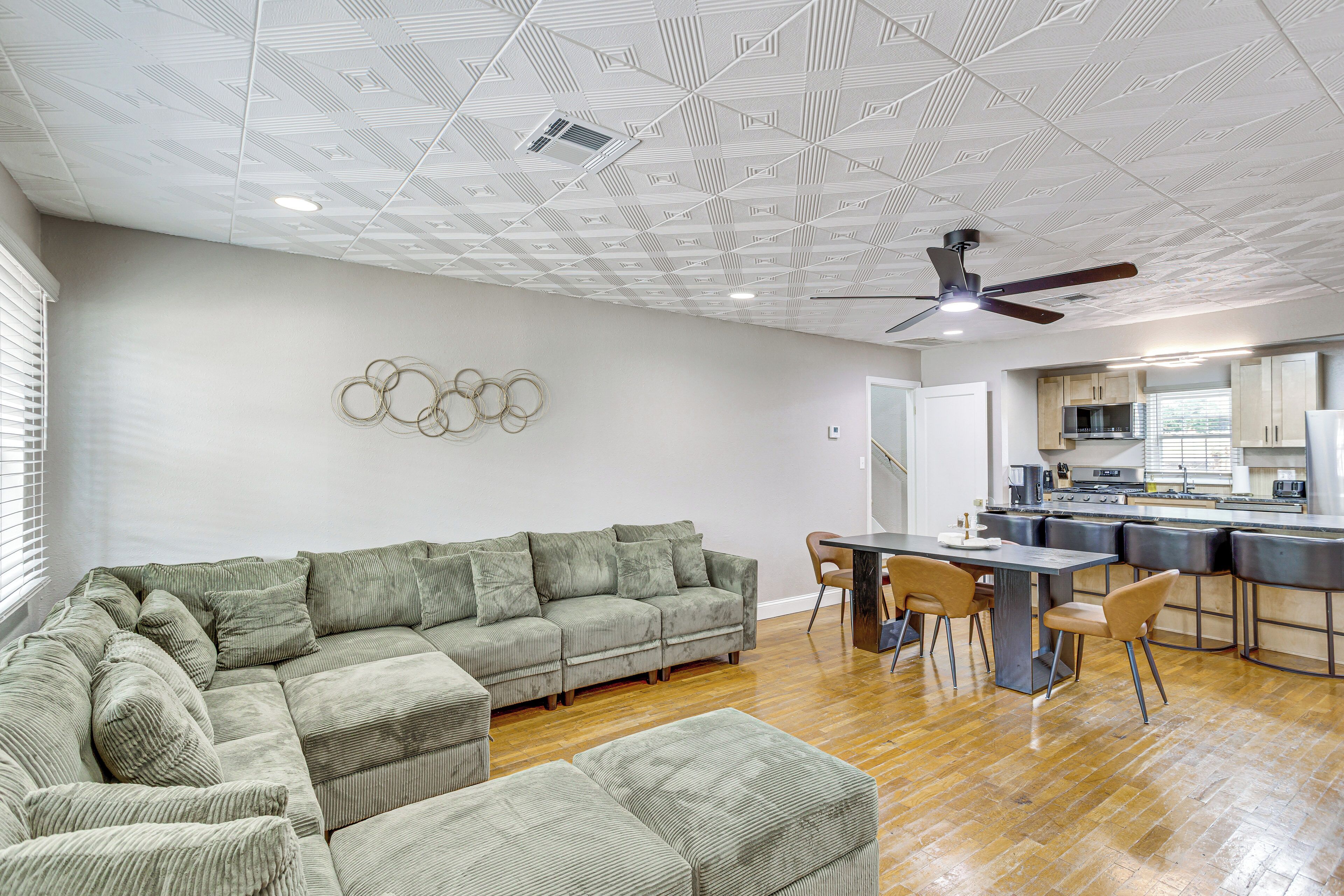 Una sala moderna con un sofá modular, una mesa de comedor con sillas y una zona de cocina con barra.