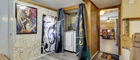 A room with a kitchen area, a dining table, and a large guitar artwork on the wall.