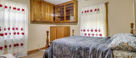 Quarto com cama, guarda-roupa de madeira e ventoinha no teto.