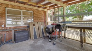 A covered patio area with a brick wall, a window, and a grill station. - Waterfront Family Home w/ Dock in Poquoson! (Poquoson)