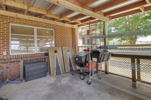 Un patio cubierto con pared de ladrillo, una ventana y una estación de parrillada.