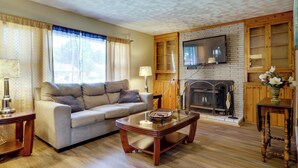 A living room with a sofa, coffee table, fireplace, television, and wooden cabinets.