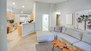 A modern living space with a kitchen, dining area, and a large grey sofa. - 4 Mi to River & Gardens! Quiet Port St Lucie Home (Port Saint Lucie)
