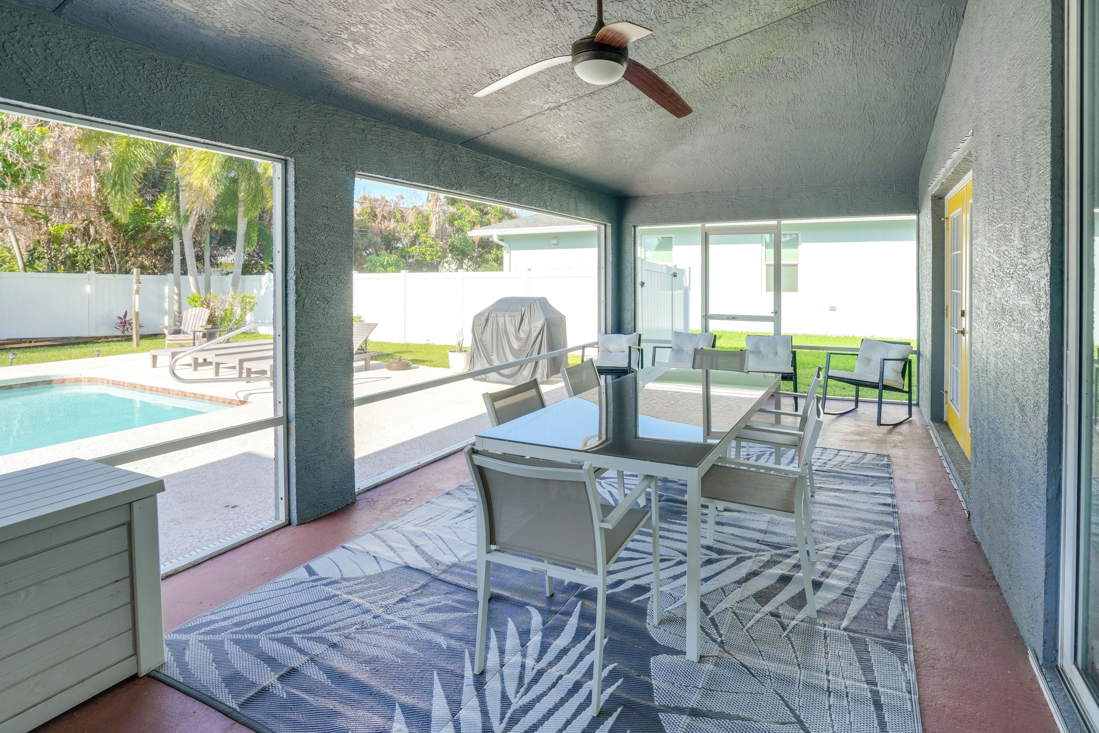 Un espace extérieur abrité comprenant une piscine, une table avec des chaises et un ventilateur de plafond.