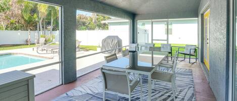 Un espace extérieur abrité comprenant une piscine, une table avec des chaises et un ventilateur de plafond.