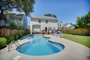 Ein Wohnpool mit Holzterrasse, überdachter Grillstelle und eingezäunter Garten.