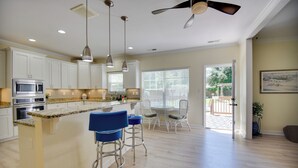 A modern kitchen with a central island, bar stools, and a dining area with a view to the outdoors. - 1 Block to Shore + Private Pool in Norfolk (Norfolk)