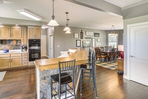 A kitchen with wooden cabinets, a built-in oven, and a bar area with stools.