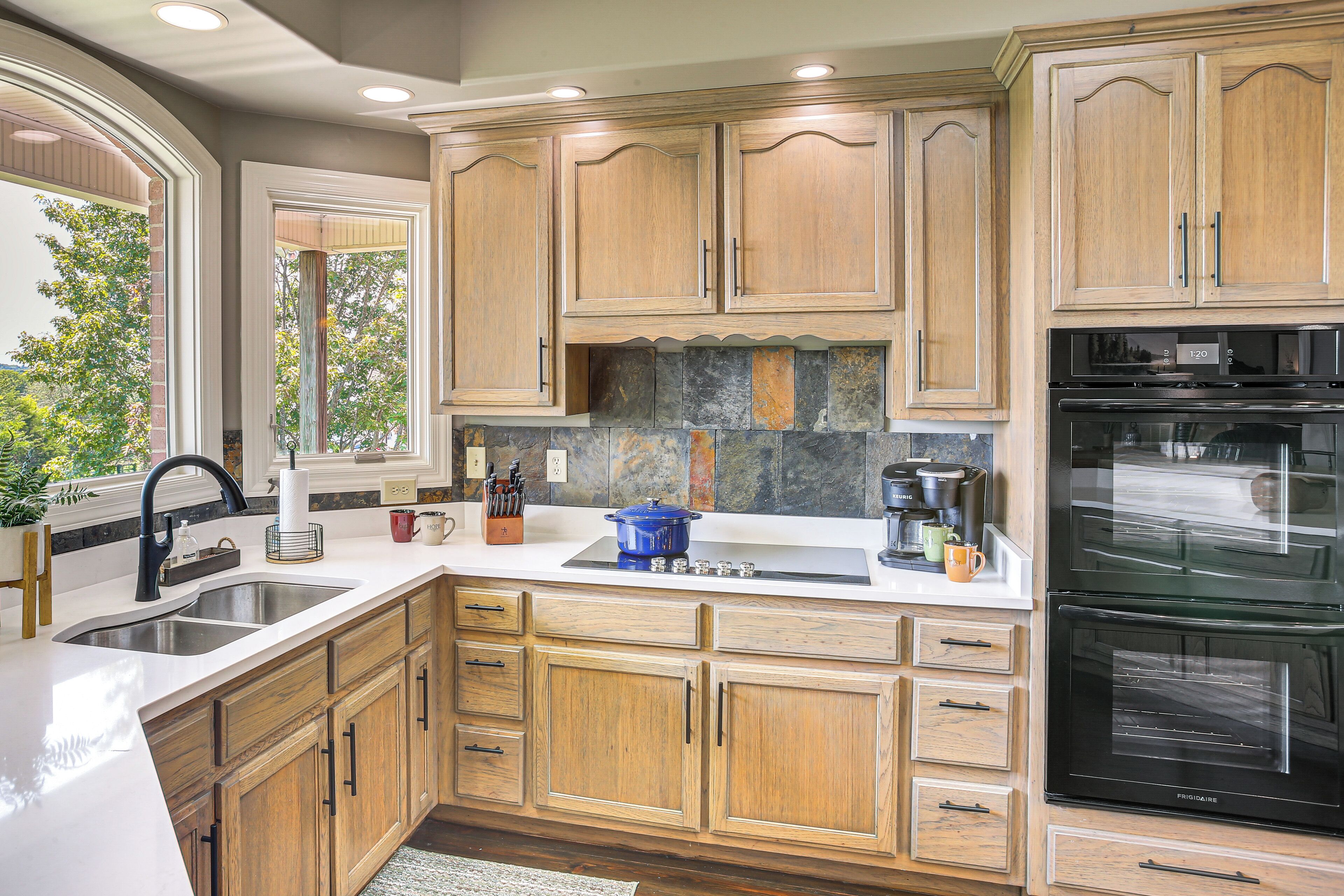 A kitchen with wooden cabinets, a black oven, and a stone backsplash.