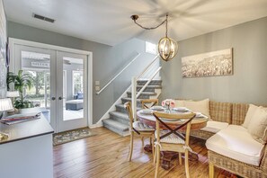 A living room with a dining table, chairs, a sofa, and a staircase leading to another level. - Updated Home Minutes to Downtown and Beach! (Sister Bay)