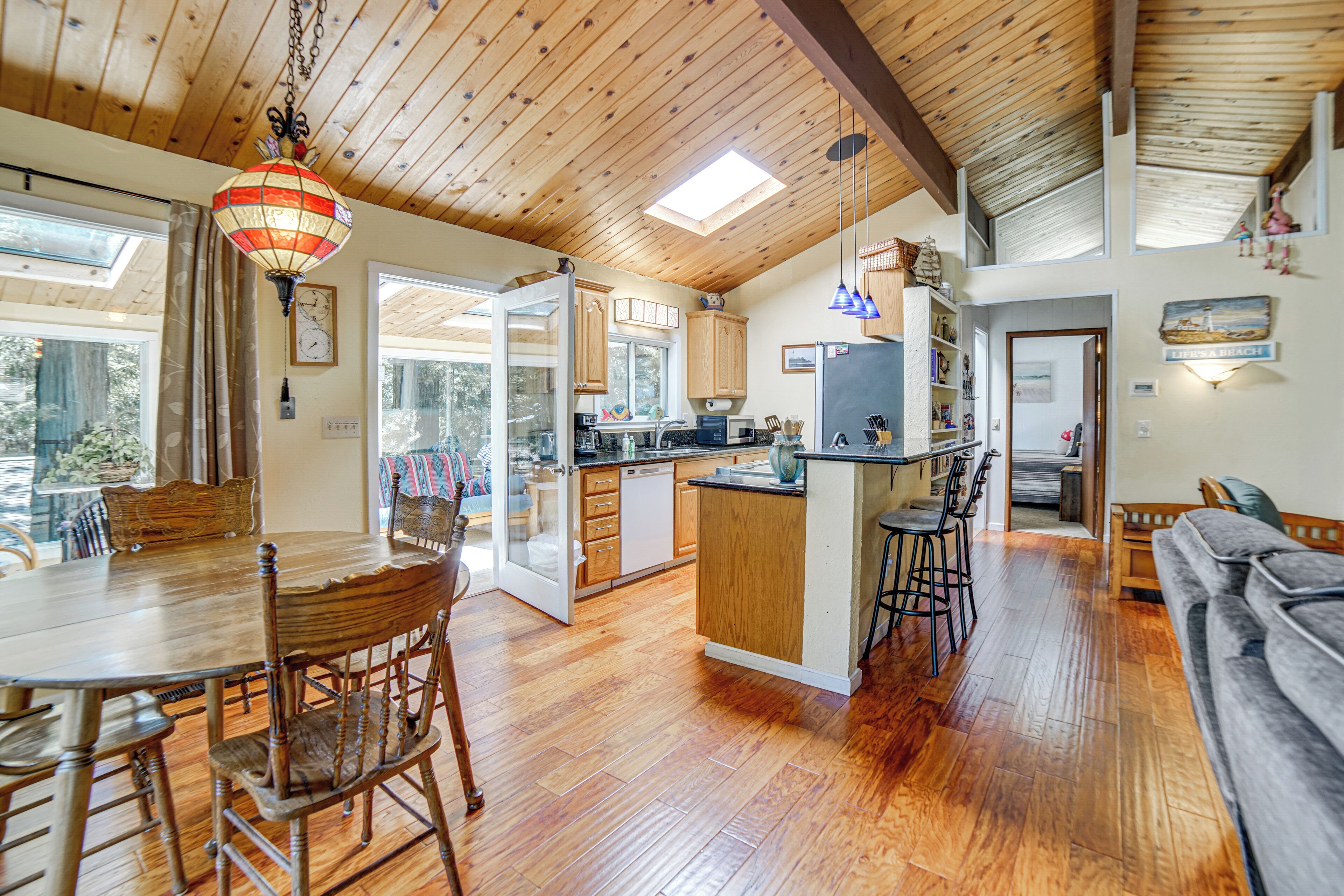 A spacious kitchen with wooden cabinets, a dining area with a wooden table and chairs, and a view of the outdoors through large windows.