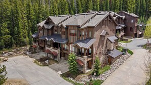 Eine mehrstöckige Blockhütte mit Steinunterbau, mehreren Balkonen und einer Auffahrt zu einem verschlossenen Eingang.