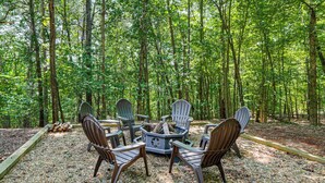 A circular arrangement of Adirondack chairs around a central fire pit in a forested area. - Ellijay Cabin Hot Tub, Mtn Views & Game Room (Ellijay)