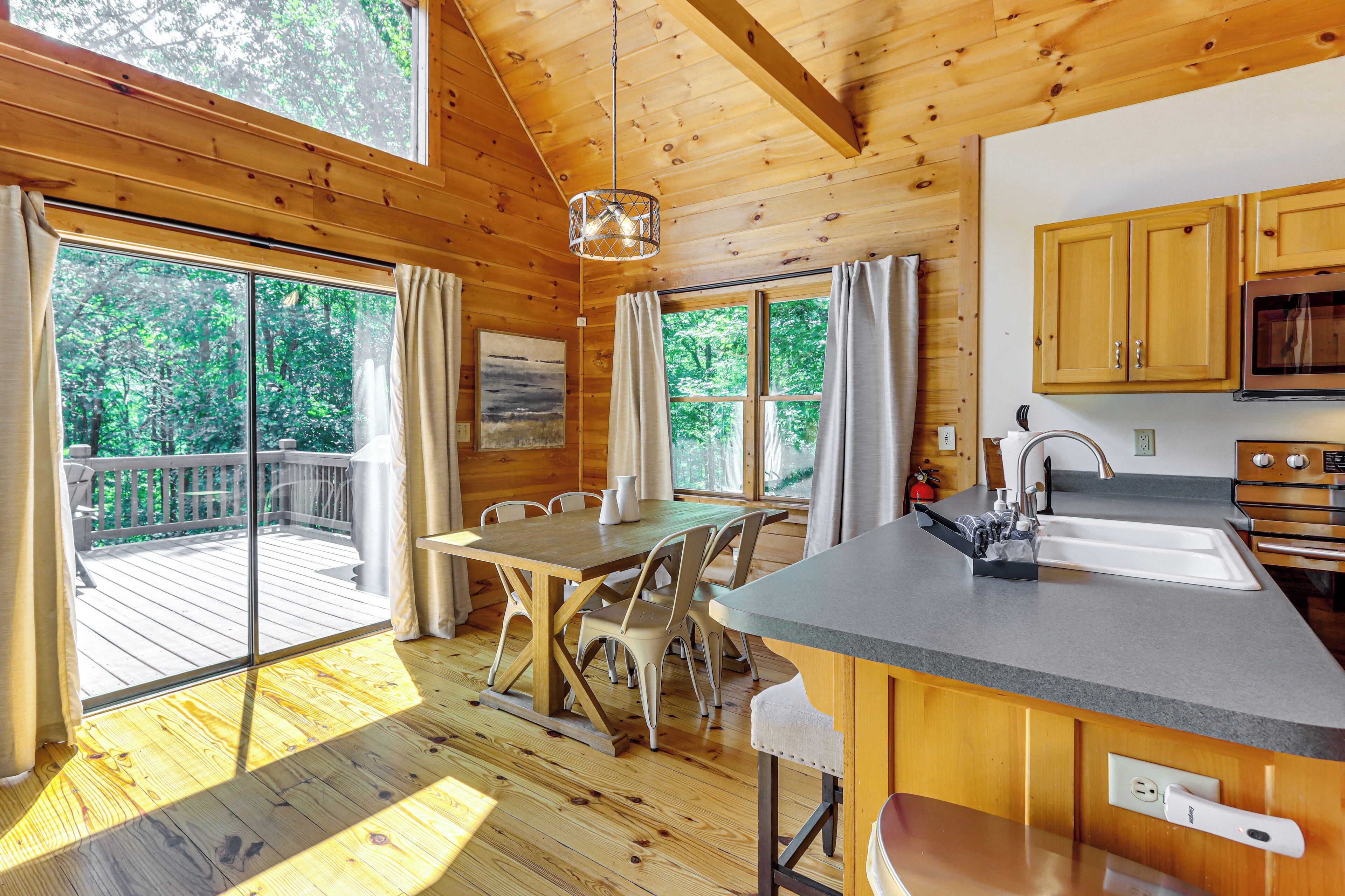 Ein Holzblock-Interieur mit Essbereich, Küche und großen Fenstern, die Blick auf einen Wald bieten.
