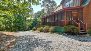 A wooden cabin with a covered porch, a stone chimney, and a gravel driveway. - Ellijay Cabin Hot Tub, Mtn Views & Game Room (Ellijay)