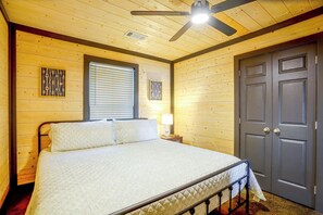 A bedroom with a bed, a ceiling fan, a window with blinds, and a door. - Walk to the Water! Kentucky Lake Cabin (Murray)