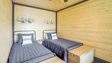 A room with two beds, a wooden wall, and a ceiling fan.