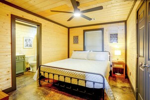 Un dormitorio con cama, ventilador de techo, ventana con persianas y puerta.
