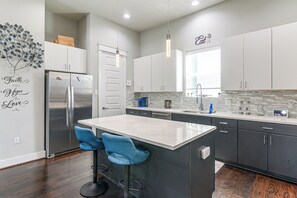 A modern kitchen with a central island, bar stools, and a refrigerator. - Walk to Astrodome! Houston Home w/ Balcony (Houston)