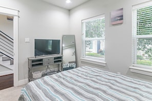 A bedroom with a bed, a TV, a window with blinds, a door, and a staircase. - Walk to Astrodome! Houston Home w/ Balcony (Houston)