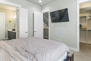 A bedroom with a bed, a TV mounted on the wall, and a closet with a mirror. - Walk to Astrodome! Houston Home w/ Balcony (Houston)