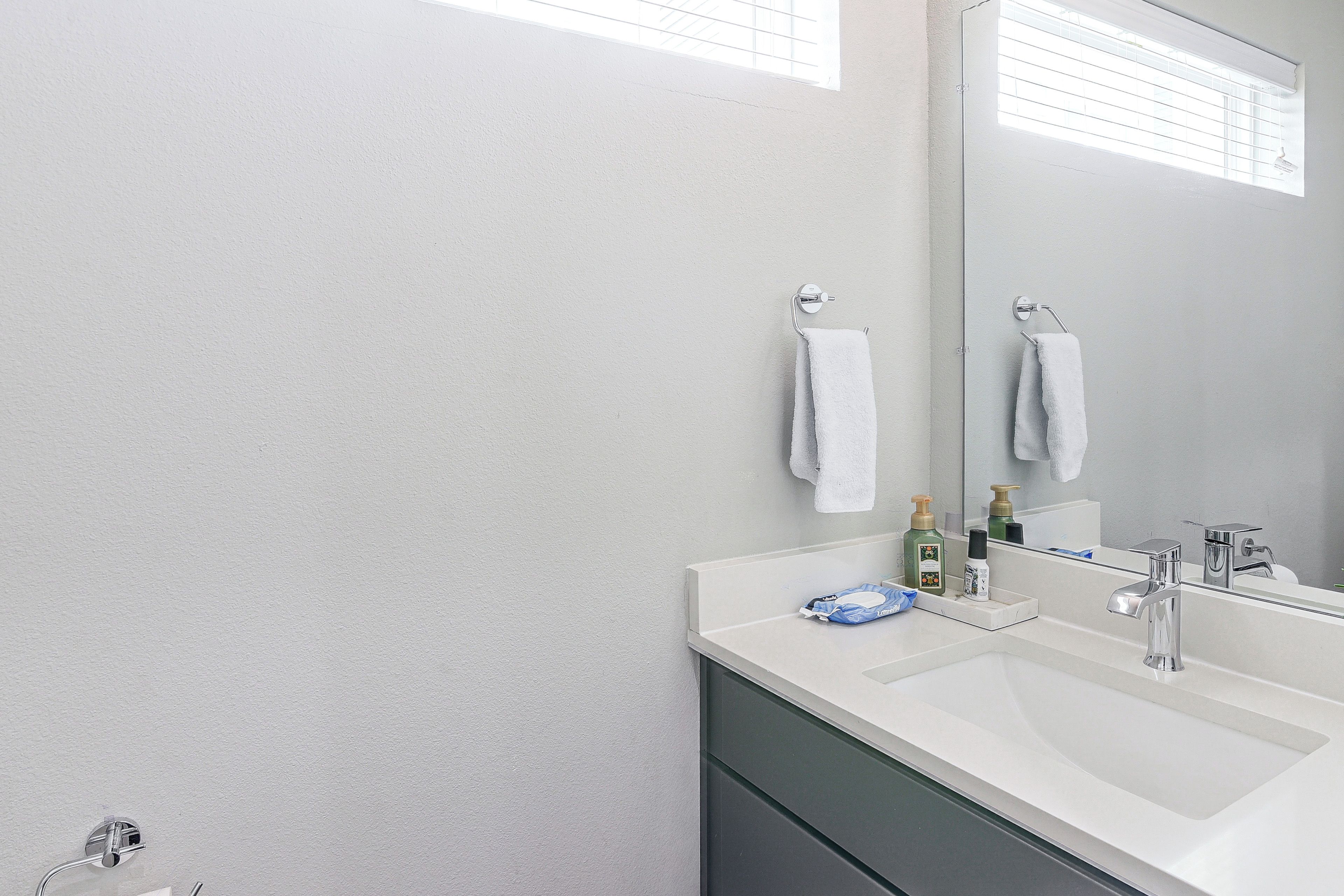 A bathroom with a white sink, a mirror, and two towels hanging on towel racks.