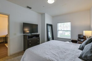 A bedroom with a bed, a television on a stand, a dresser, a mirror, and a window with blinds. - Unwind Poolside, Explore Wdw! Kissimmee Retreat (Kissimmee)