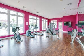 A gym with various exercise equipment, large windows, and a flat-screen TV. - Unwind Poolside, Explore Wdw! Kissimmee Retreat (Kissimmee)