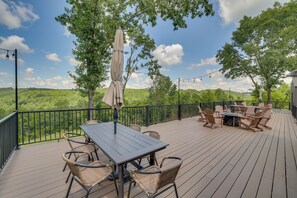 Eine Terrasse mit Gartenmöbeln, einem Tisch und Stühlen, umgeben von einem Geländer und Bäumen.
