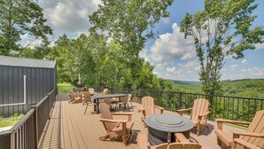 Un terrazzo con mobili da esterno, un barbecue e vista su un paesaggio boschivo.