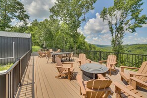 Eine Terrasse mit Gartenmöbeln, einem Grill und Blick auf eine bewaldete Landschaft.