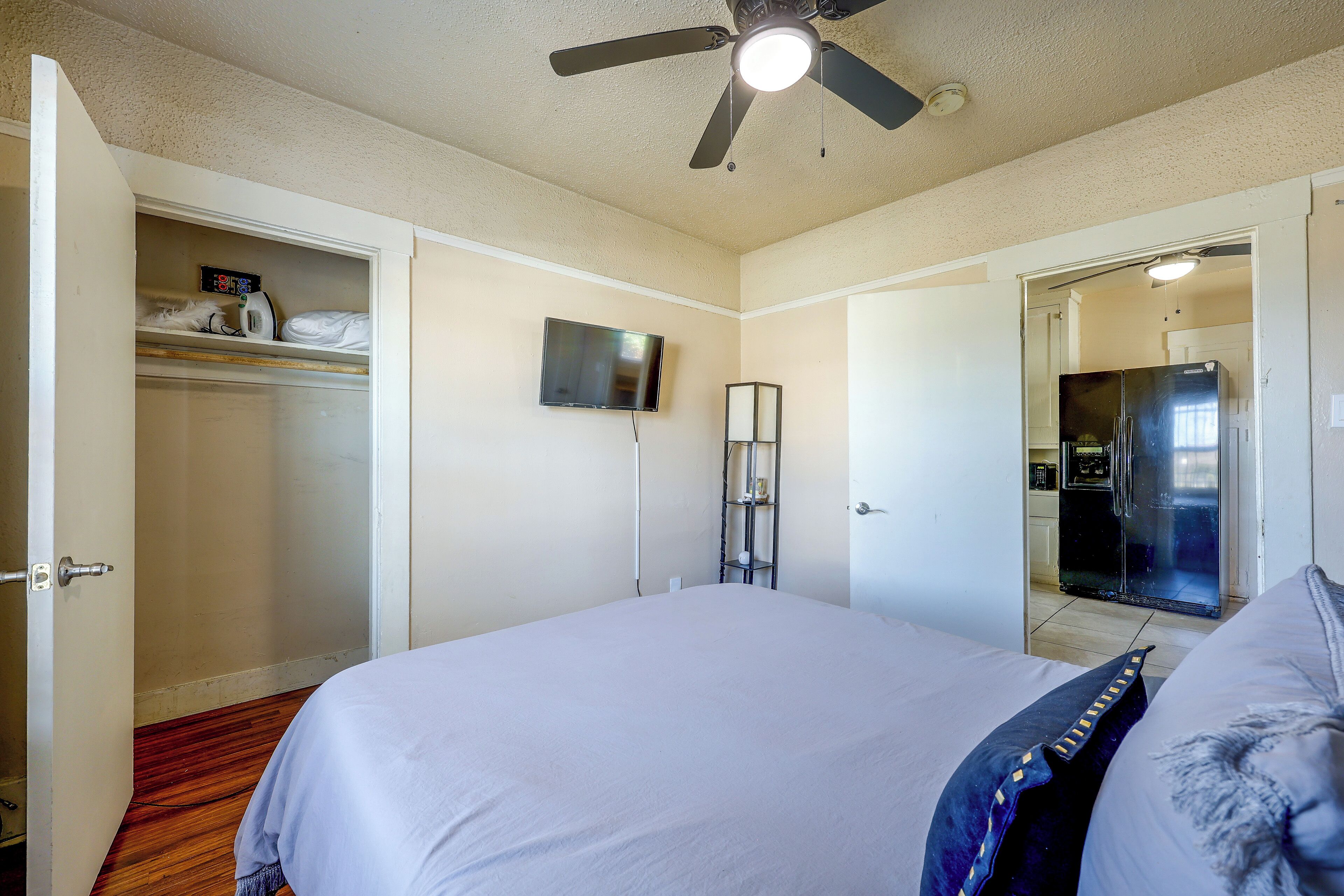 A bedroom with a bed, a ceiling fan, a television, and a wardrobe.
